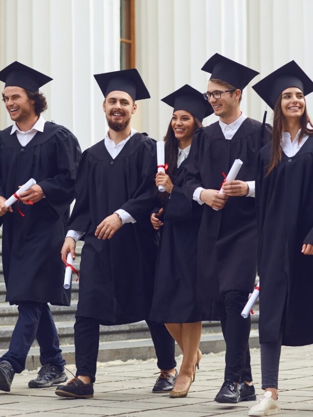 Successful graduates in academic dresses are walking and talking outdoors