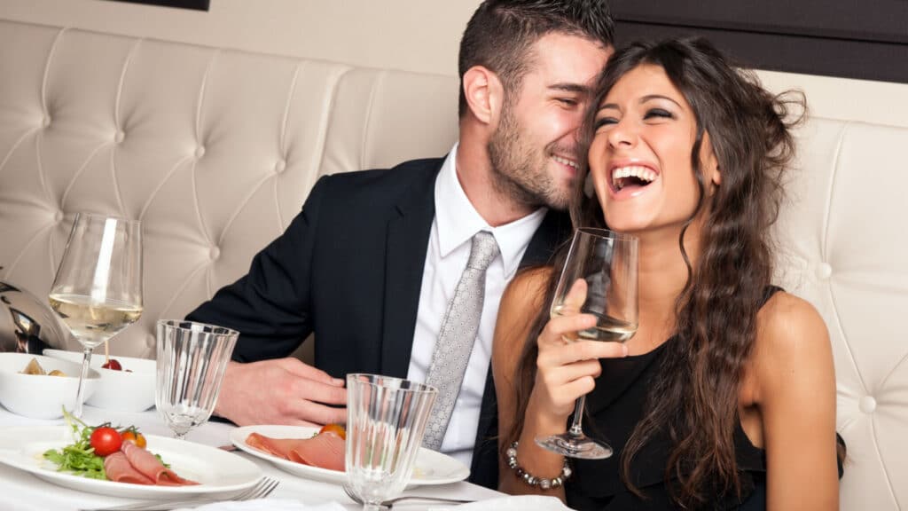 Attractive elegant young couple drinking a cocktail at the restaurant and laughing