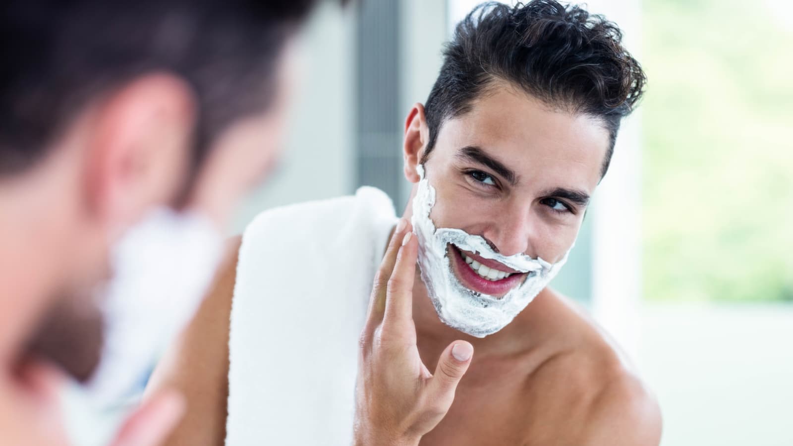 Handsome man shaving his beard in bathroom