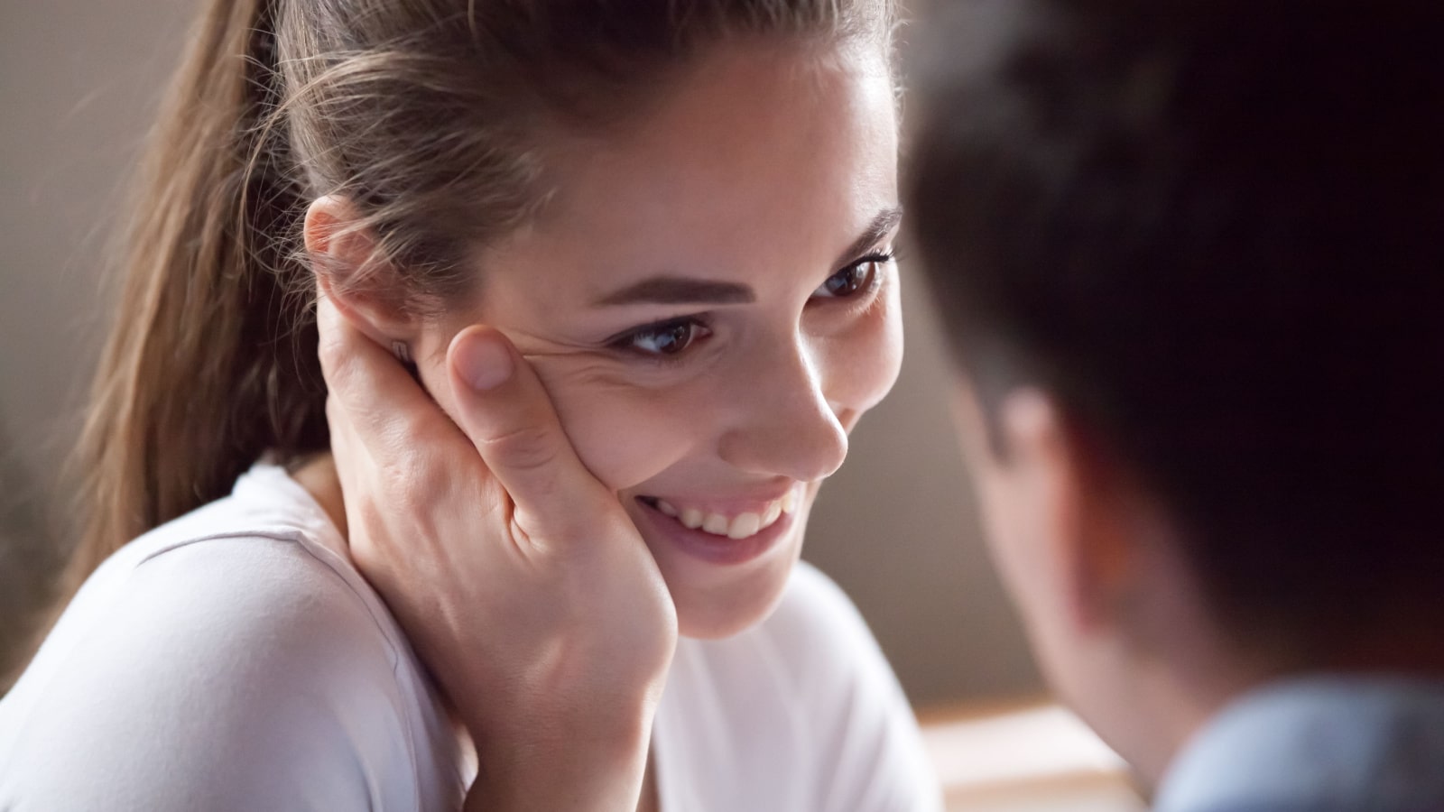 Close up millennial couple in love with focus on brunette girl. Portrait of smiling woman touched stroked by male hand. Tender relationship loving people. Family, dating, declaration of love concept