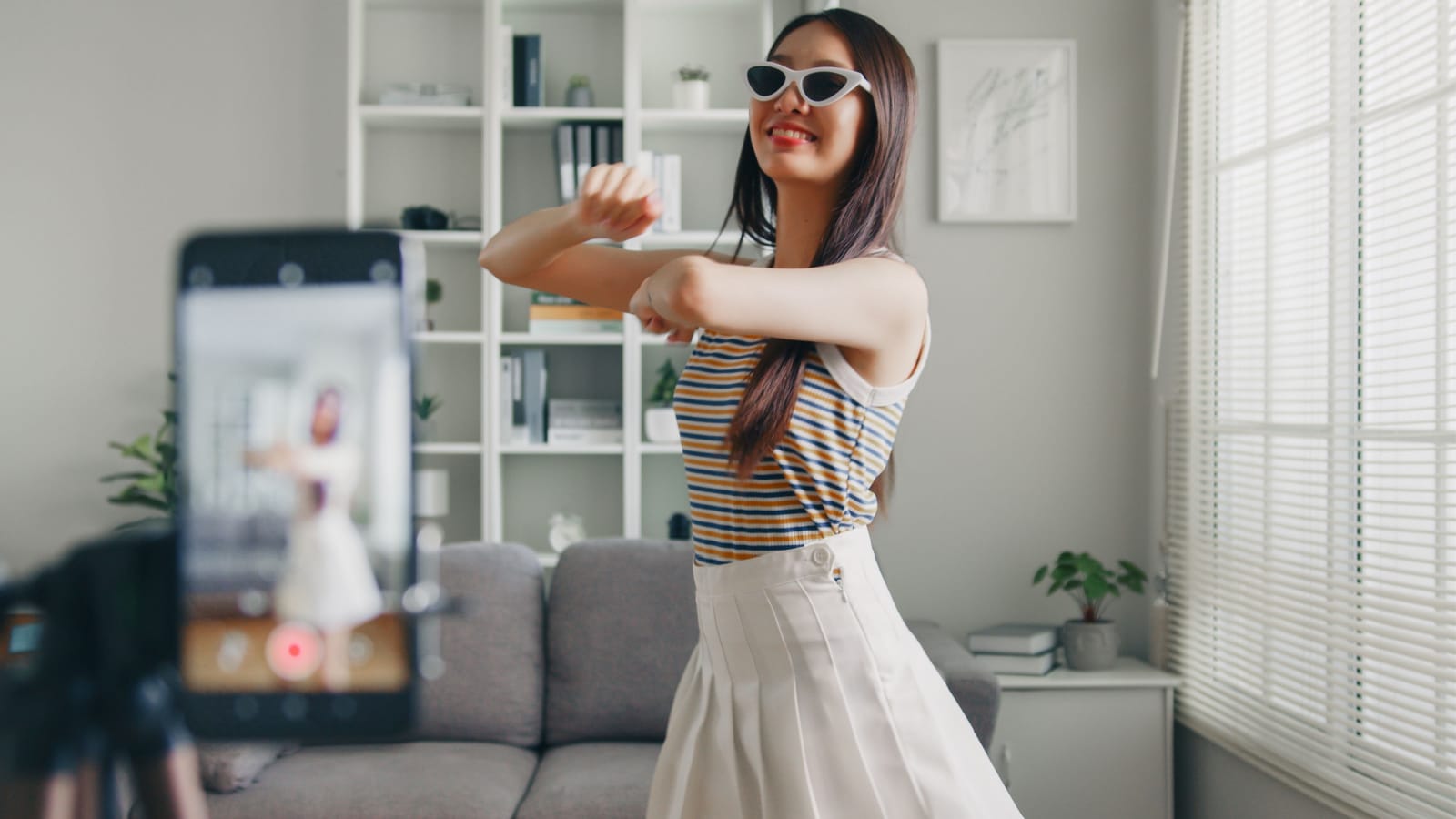 Asian young woman tiktoker created her dancing video by smartphone camera. To share video on social media application