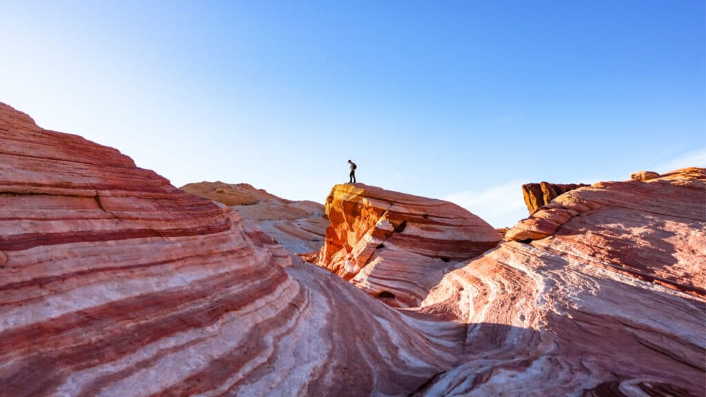 A hiker enjoys the desert views from atop the colorful Fire Wave in Valley of Fire State Park, Nevada.