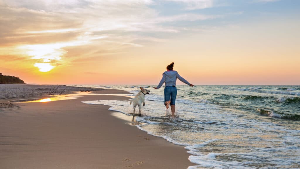 Happy woman on the beach with a dog