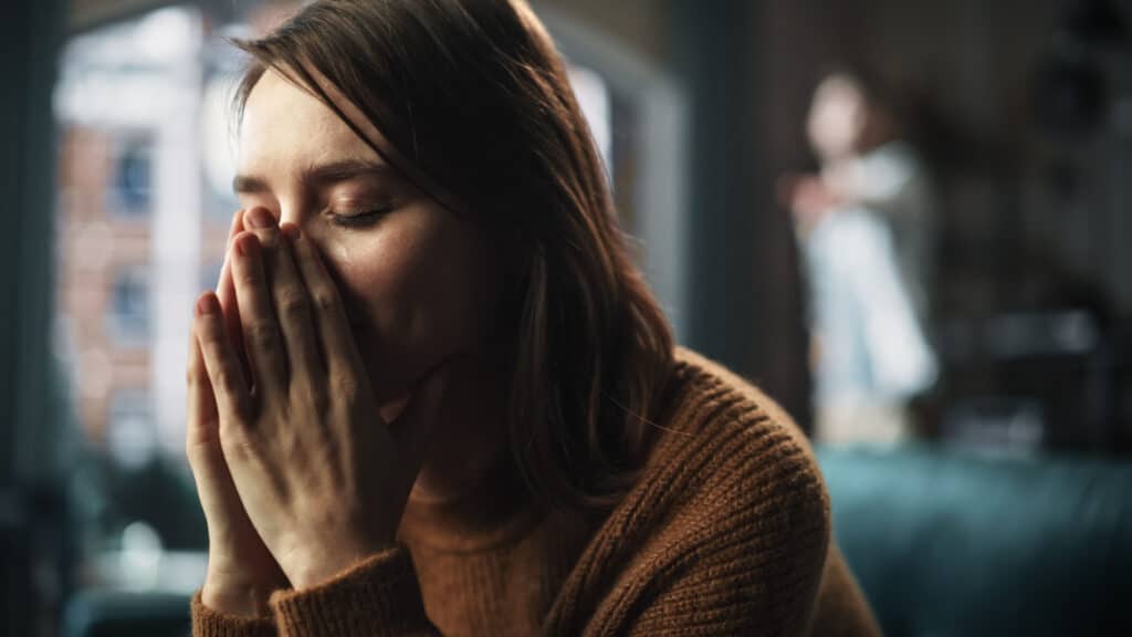 Portrait of Sad Crying Woman being Harrased and Bullied by Her Partner. Couple Arguing and Fighting Violently. Domestic Violence and Emotional Abuse. Rack Focus with Boyfriend Screaming in Backgroun