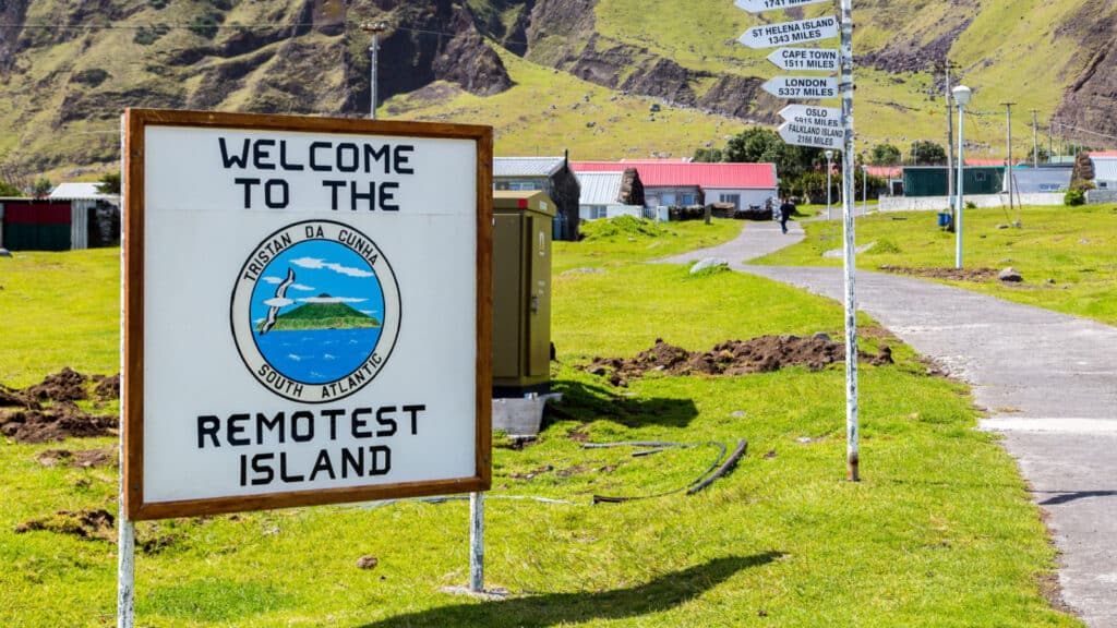 Edinburgh, Tristan da Cunha - Nov 21, 2013: Welcome to the Remotest Island touristic signpost and distance fingerposts to other places in the town centre of Edinburgh of the Seven Seas settlement