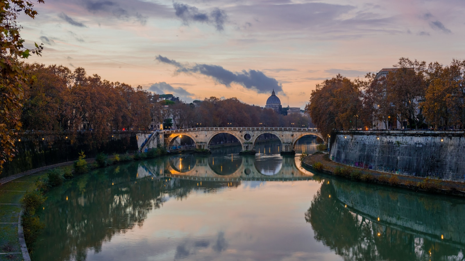 View of Ponte Sisto in the twilight, as seen from Garibaldi bridge. The dome of the St Peter's basilica is in the background. Rome, Italy, December 2018.