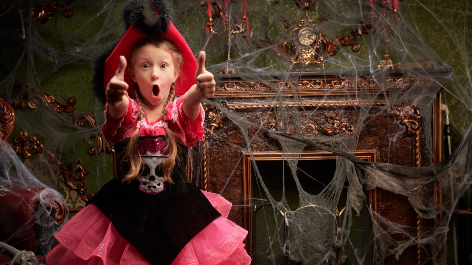 Halloween party at the haunted castle. A pretty girl in a pirate costume is very surprised, showing thumbs up. Place for text.