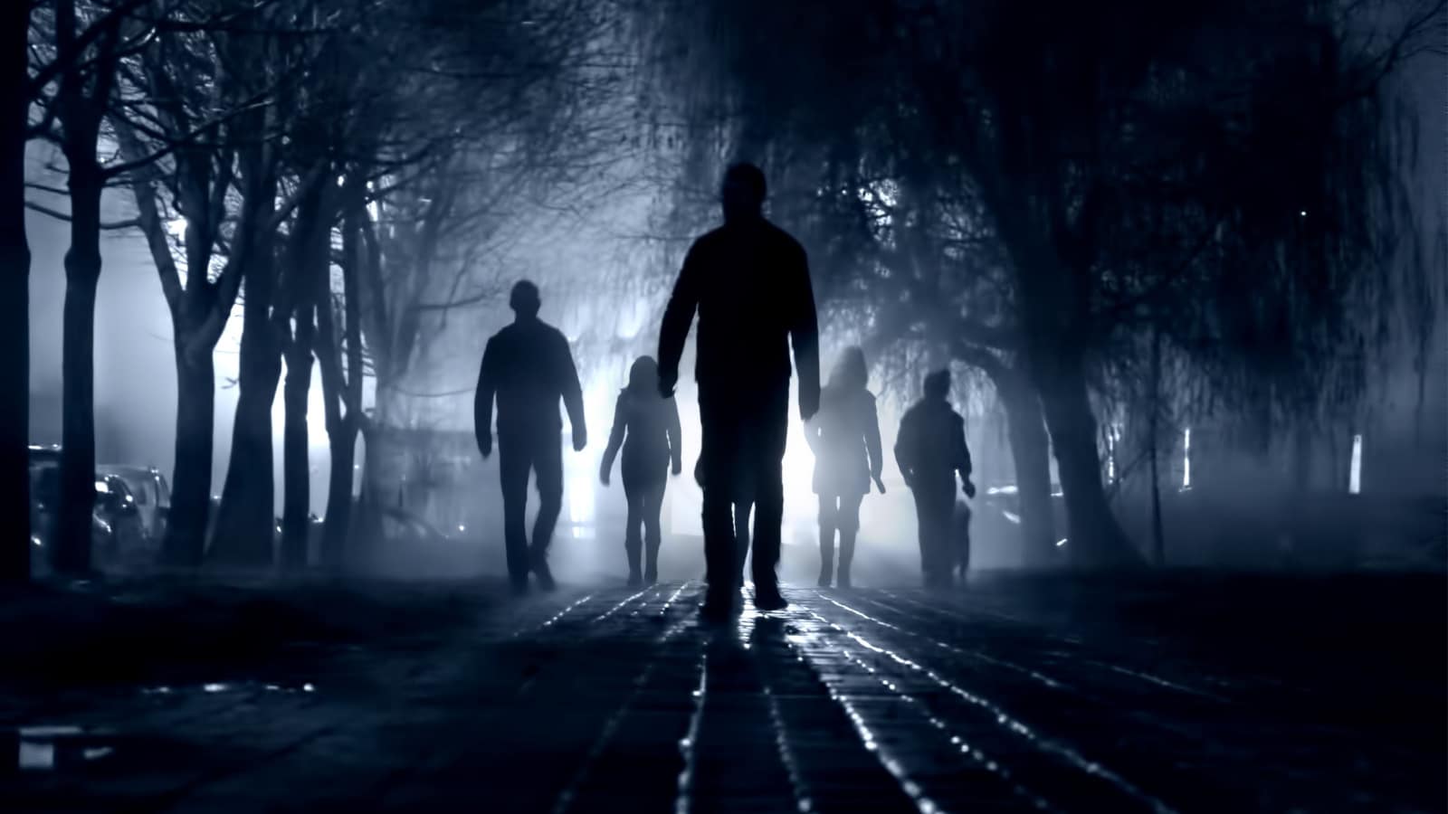 Silhouettes of people zombie walk at night in the city in the moonlight in the soft blurred focus on a dark blue background. Artistic image of a zombie people.