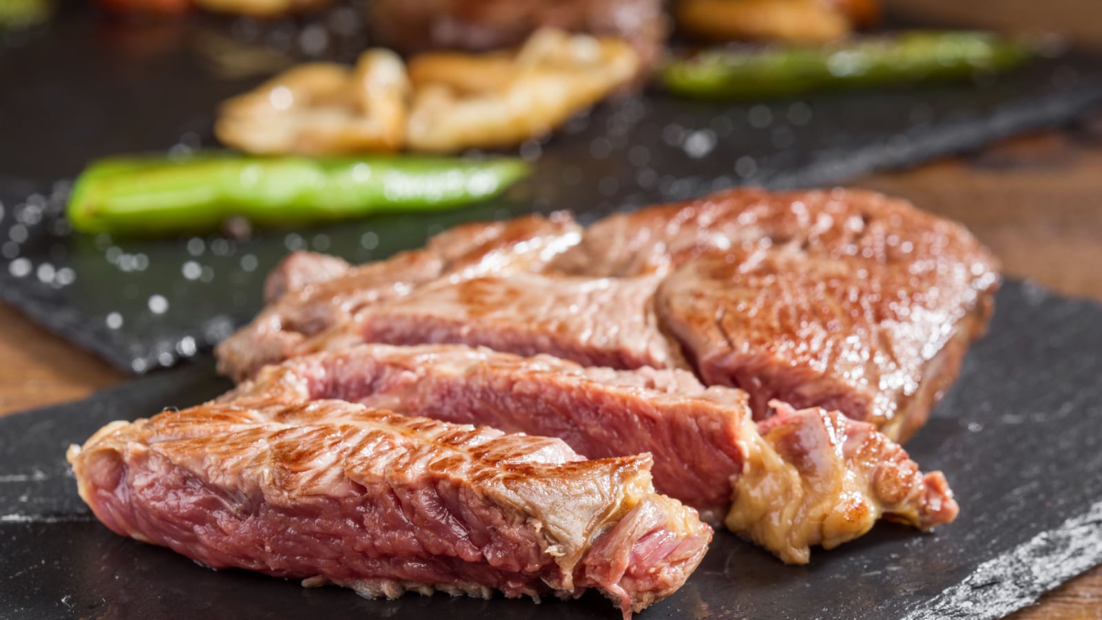 macro shot of half-cooked horse meat fillets on black stone