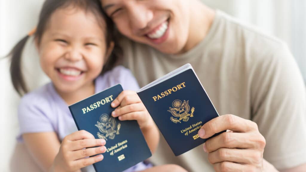 Asian dad and daughter holding amercian passports with pride. Immigration citizenship