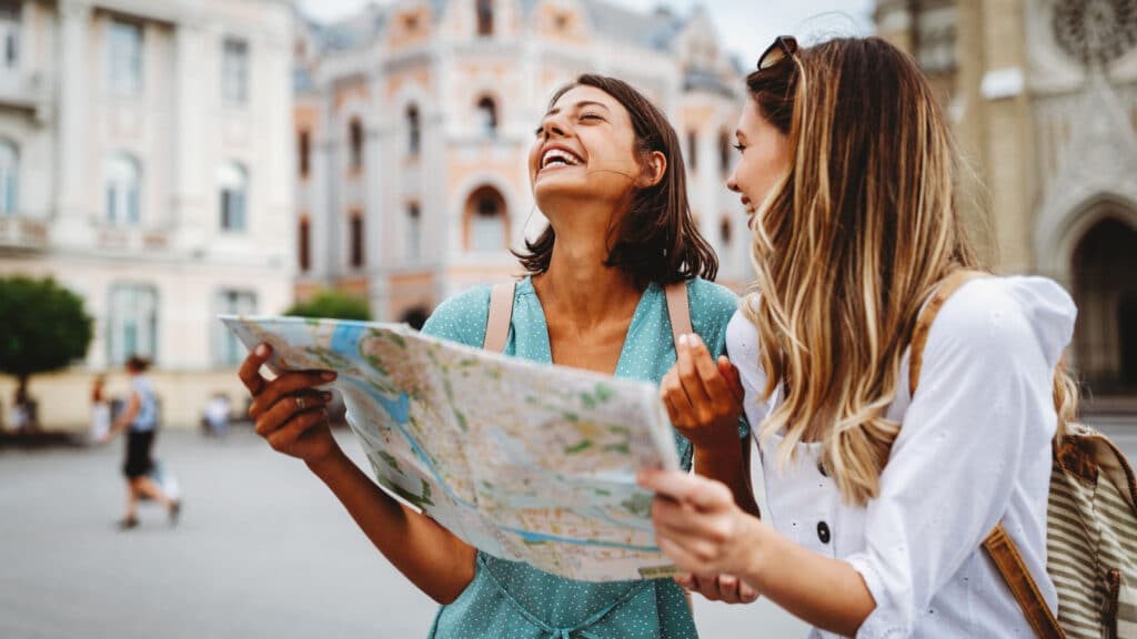 Fun, friends, travel and tourism concept. Beautiful girls looking for direction in the city