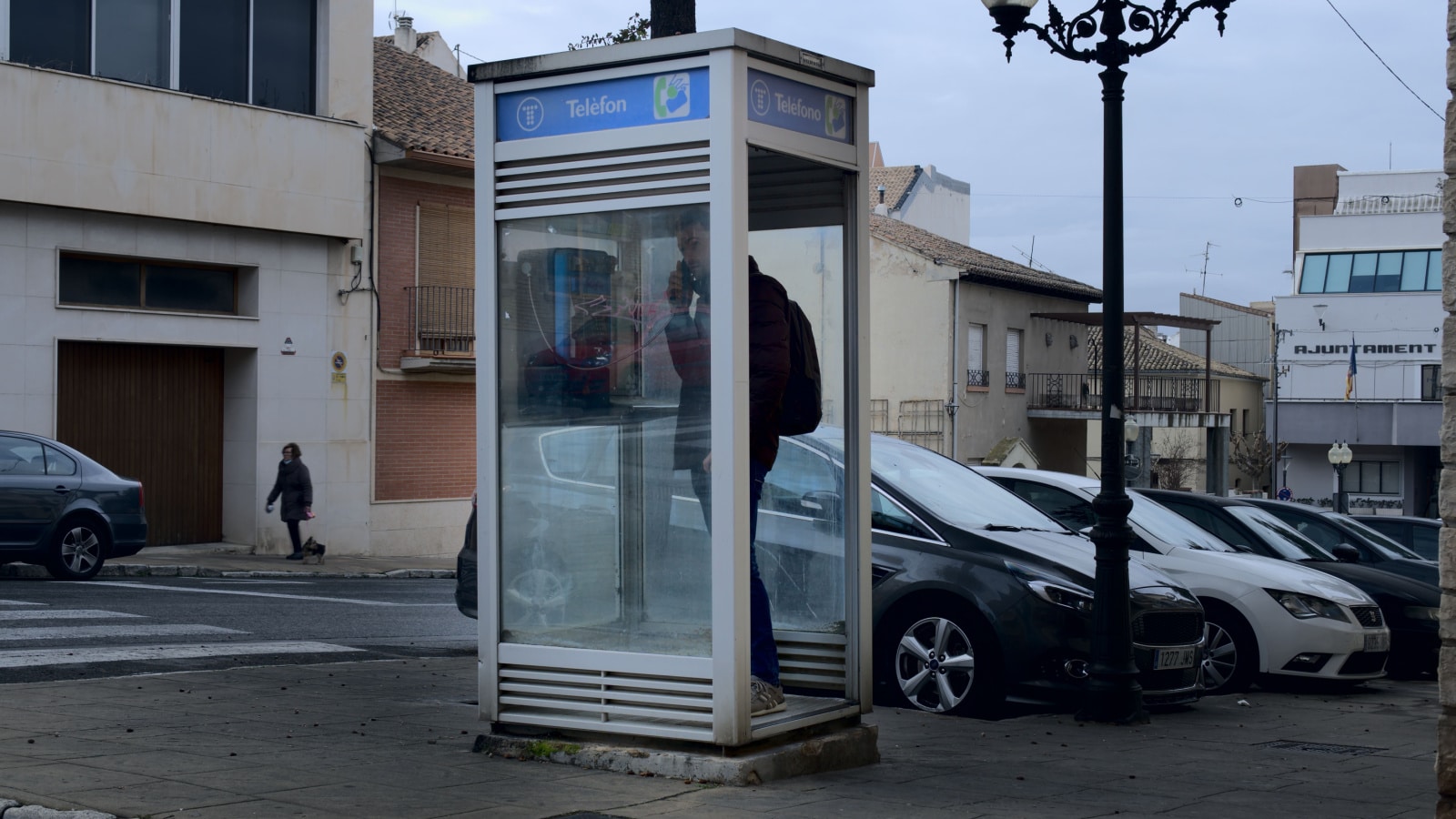 February 2022. Ibi, Alicante, Spain - Misterious man calling at a telephone booth at the street. All phone booths are being removed from all the country. High quality photo