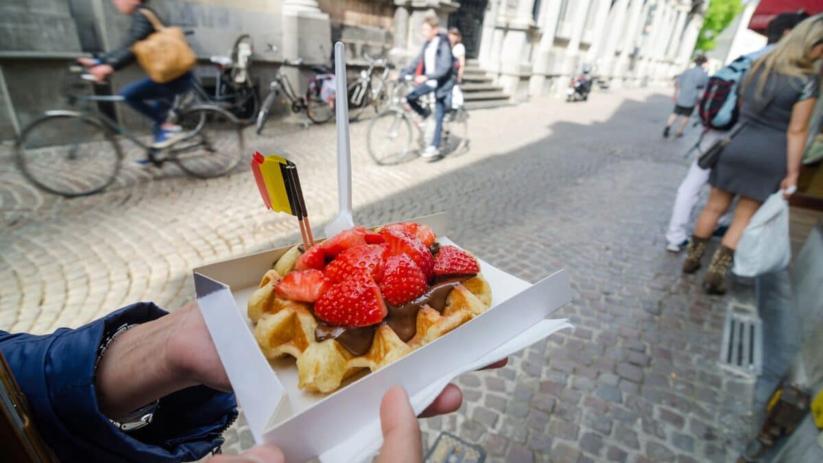 Belgium waffle with chocolate sauce and strawberries, Bruges city background