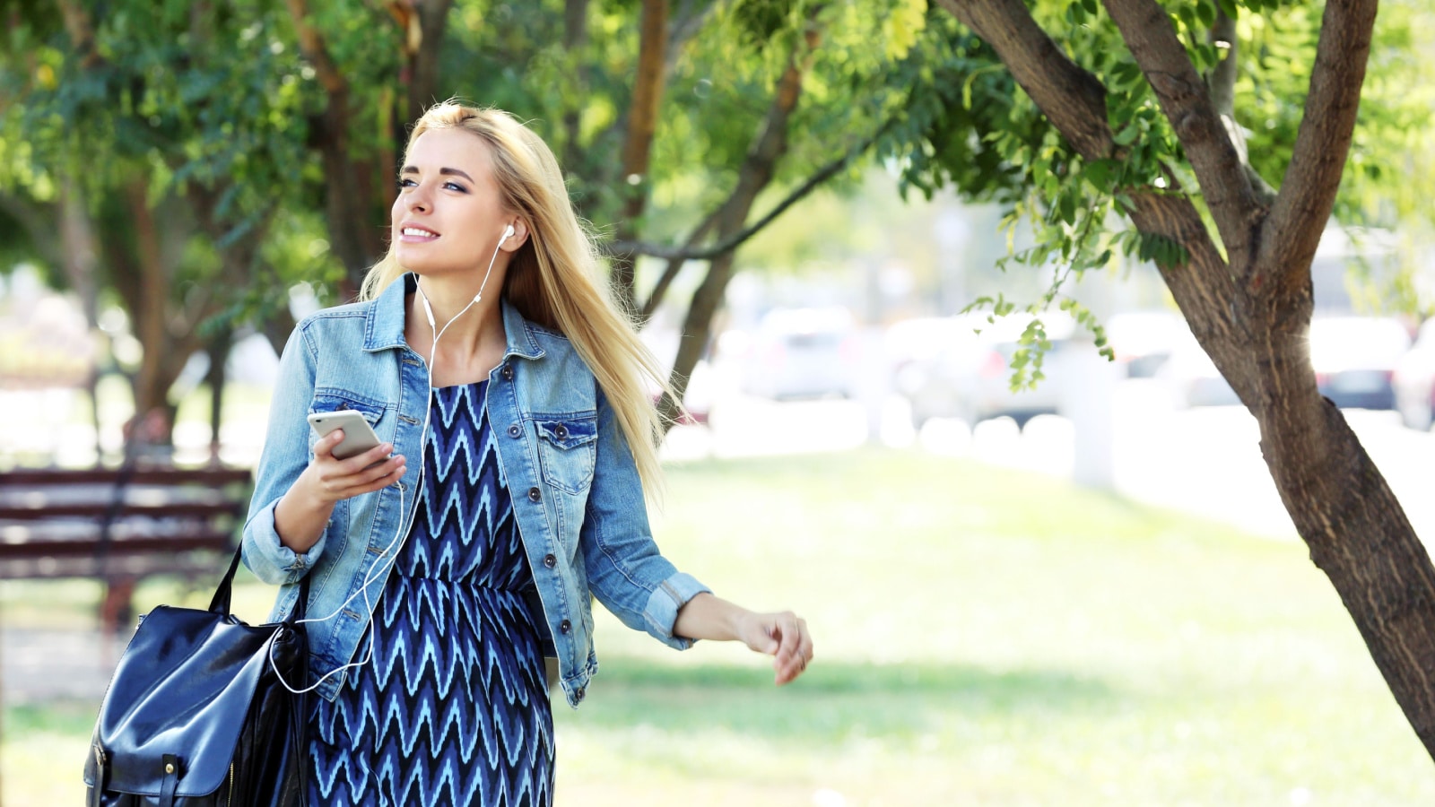 Young woman listening to music and walking in the park