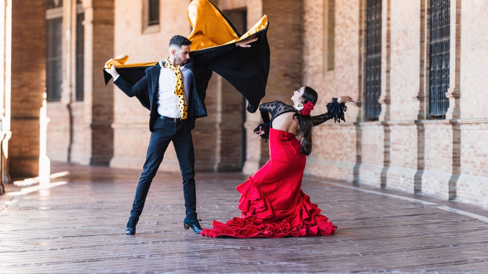 Man and woman in flamenco costume performing a dance on the shadow of the Spain Square in Seville