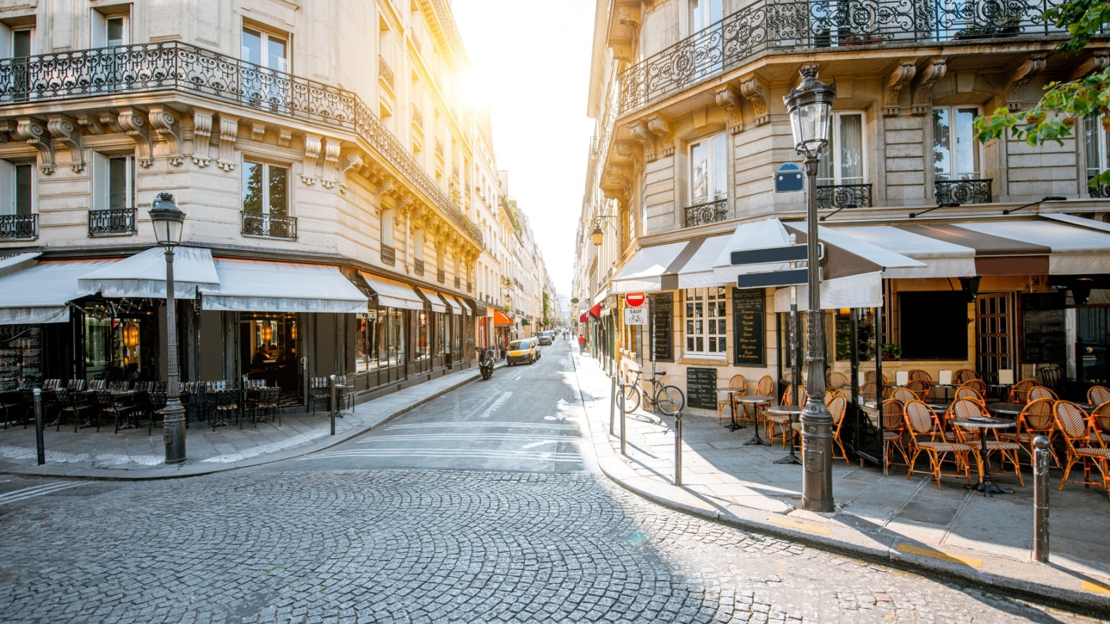 Street view with beautiful buildings and cafe terrace during the morning light in Paris