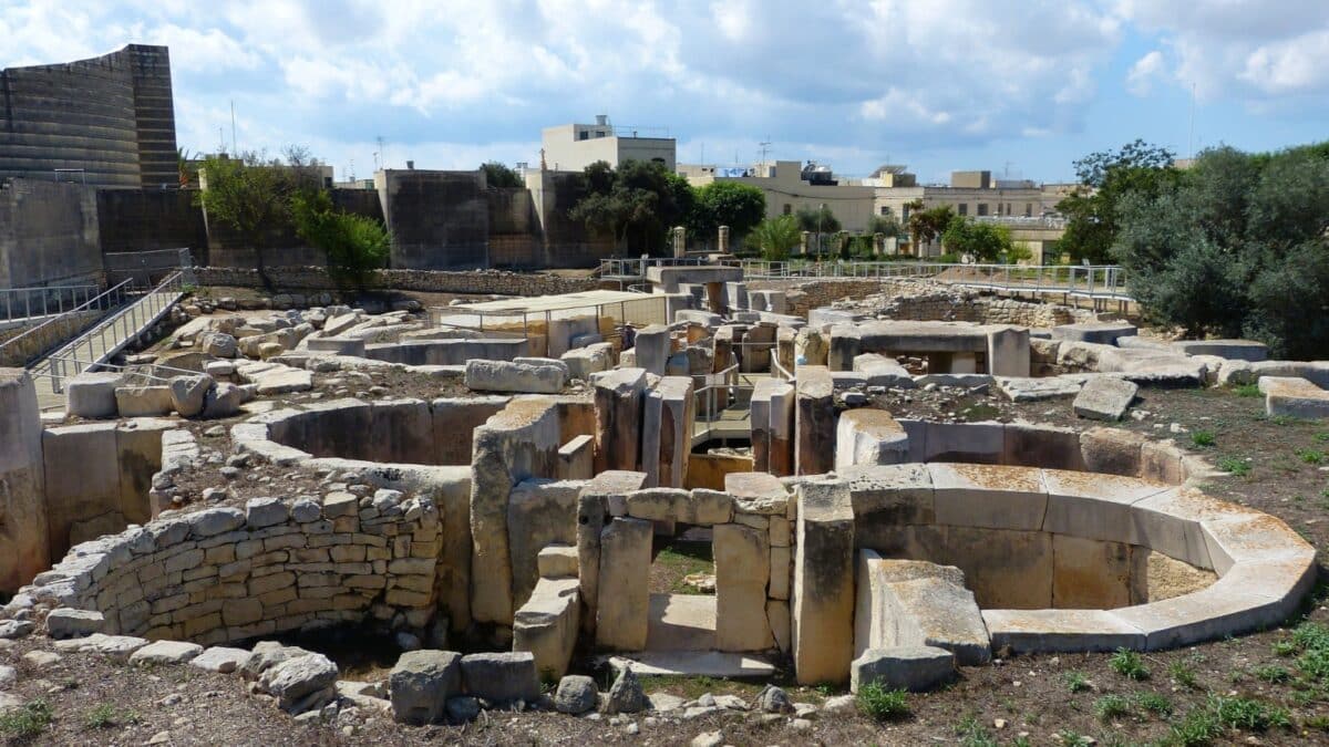 TARXIEN, MALTA - SEPTEMBER 23, 2013. Megalithic structures of the Tarxien Temples with neolithic megaliths, walkways and residential buildigs in the background.