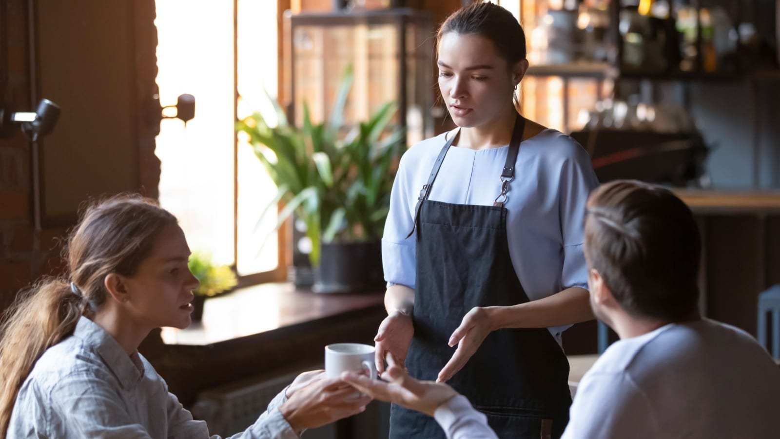 Angry couple client talk dispute with millennial waitress feel dissatisfied with cafe bad service, mad disappointed customers speak with staff complain