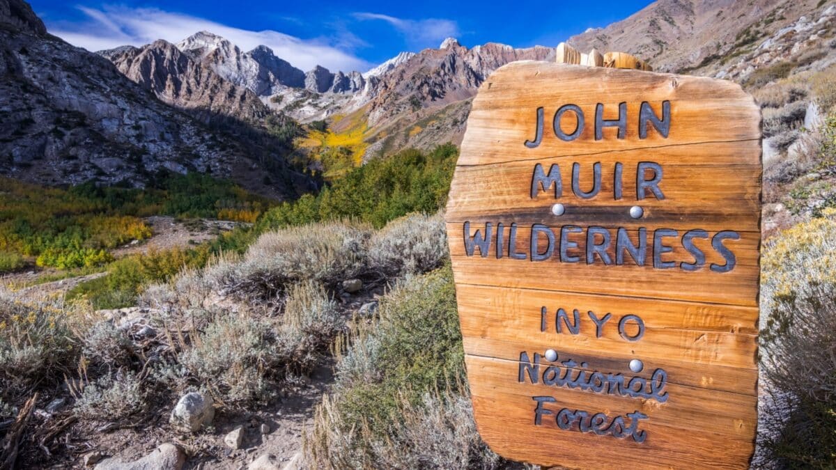 Sign posted at the entrance to the John Muir Wilderness, in the Inyo National Forest; Eastern Sierra mountains, California; McGee valley visible in the background; beautiful sunny fall day