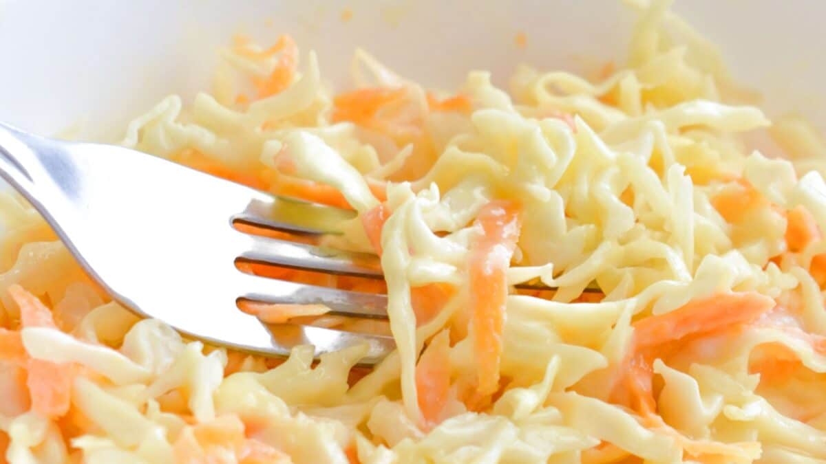 Coleslaw salad with carrot and cabbage on a white bowl.