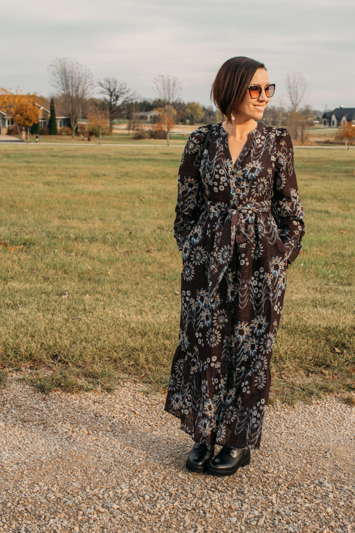 Lindsey with her hands in her pockets wear a Marie Oliver dress