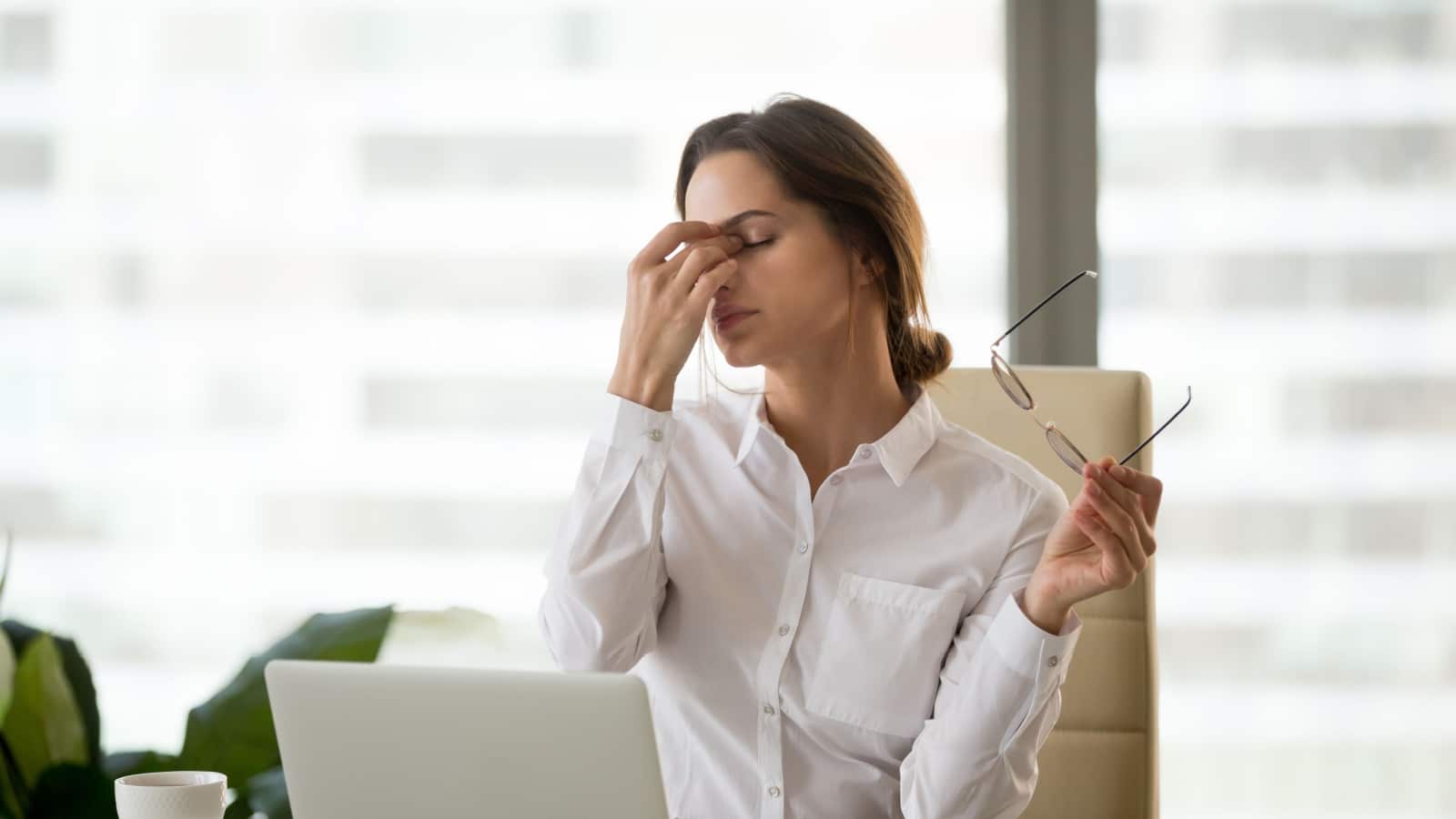 Fatigued businesswoman taking off glasses tired of computer work, exhausted employee suffering from blurry vision symptoms after long laptop use, overworked woman feels eye strain tension problem