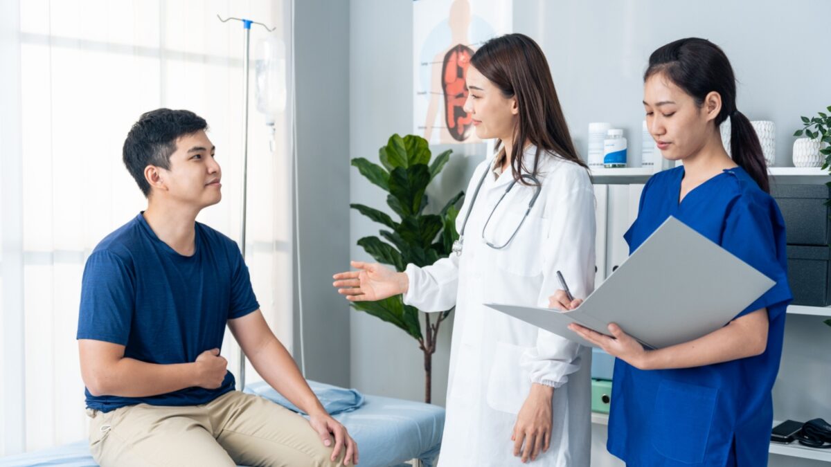 Asian specialist doctor and assistant nurse take care of male patient. Professional female physician team explain diagnosis and advise service treatment to sick person in hospital during appointment.