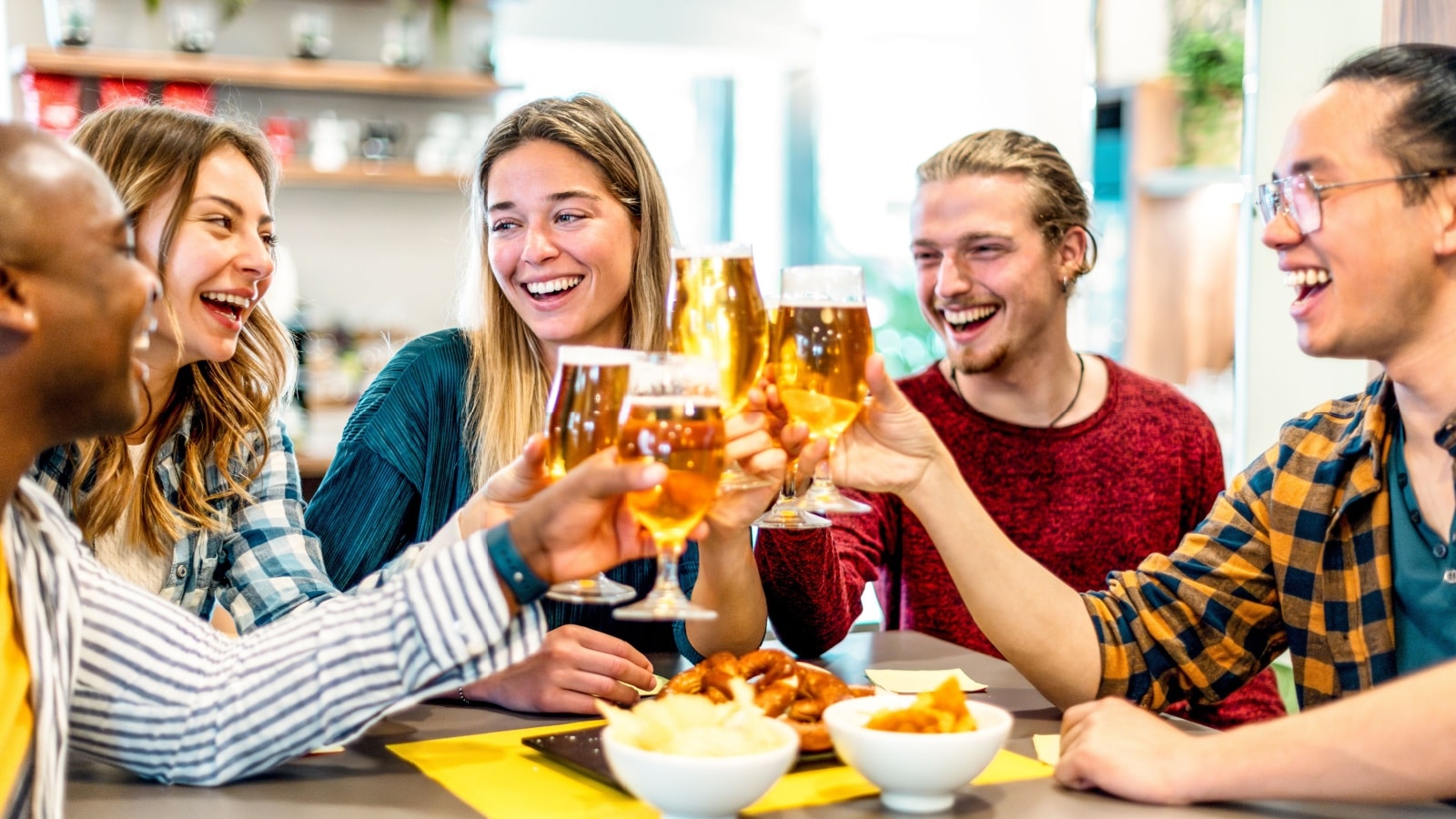 Happy friends drinking beer at brewery bar restaurant on weekend - Friendship concept with young smiling people having fun together toasting brew pint on happy hour at pub - Men and women at home