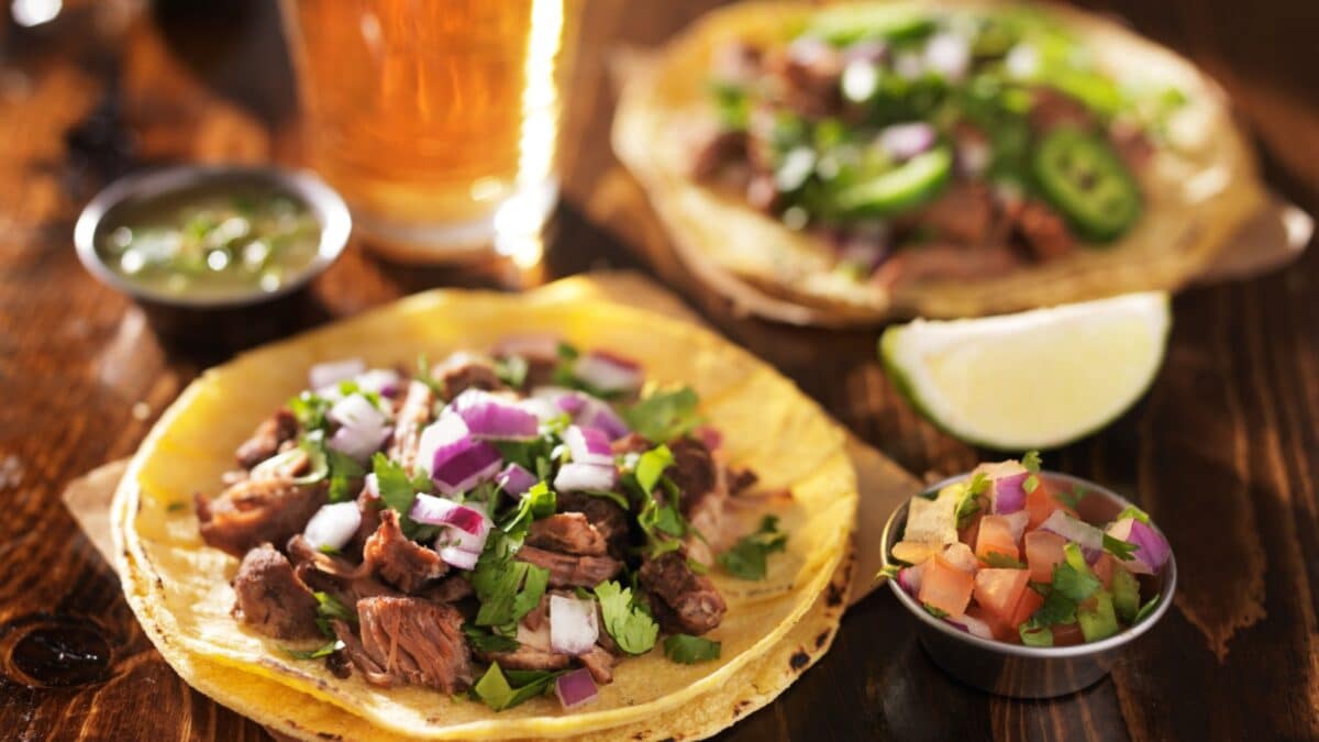 authentic mexican tacos with beer on wooden table shot with selective focus