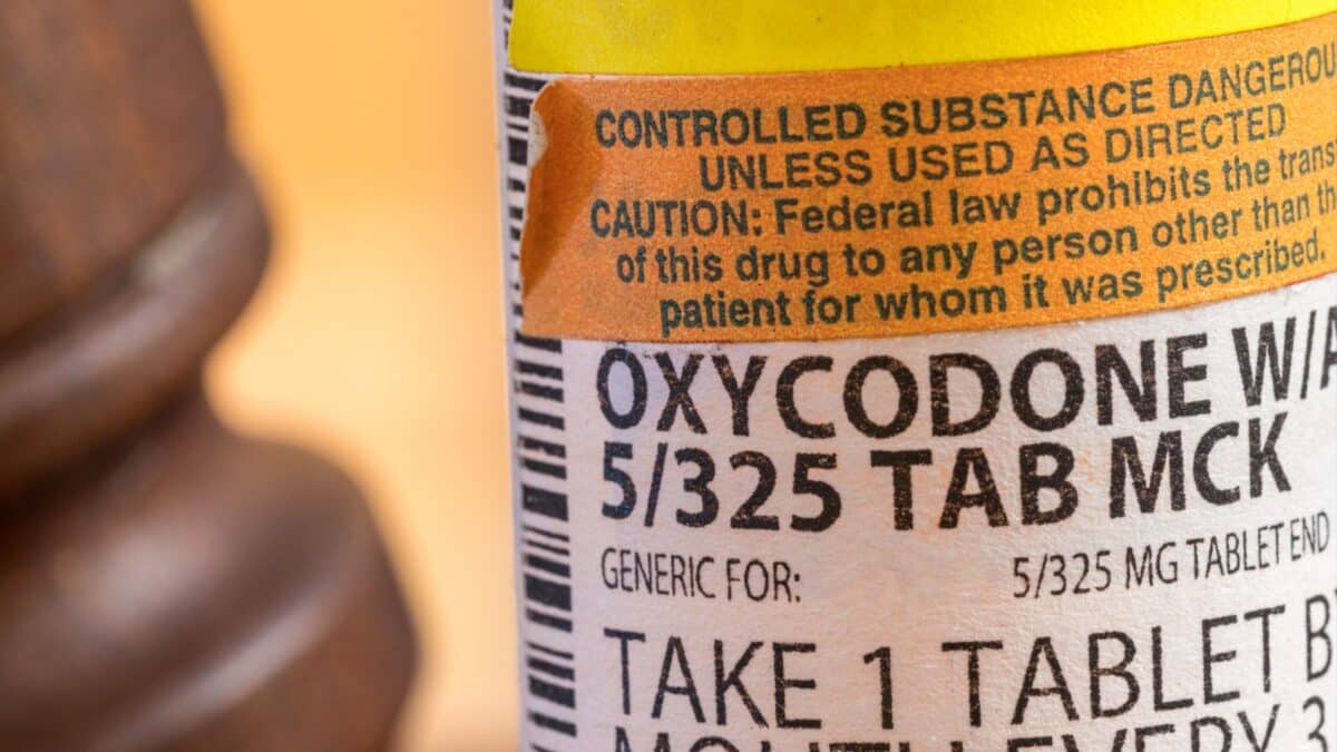 Morgantown, WV - April 4, 2021: Prescription bottle for Oxycodone pills and tablets with focus on the medication with judges gavel in background