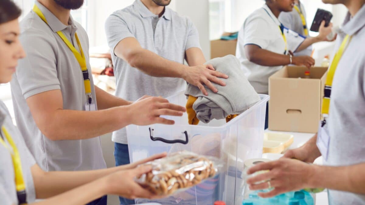 Volunteers working at humanitarian aid center. Diverse Caucasian and African American men and women collect food and clothes to take them to people in refugee shelters. Help, charity, donation concept