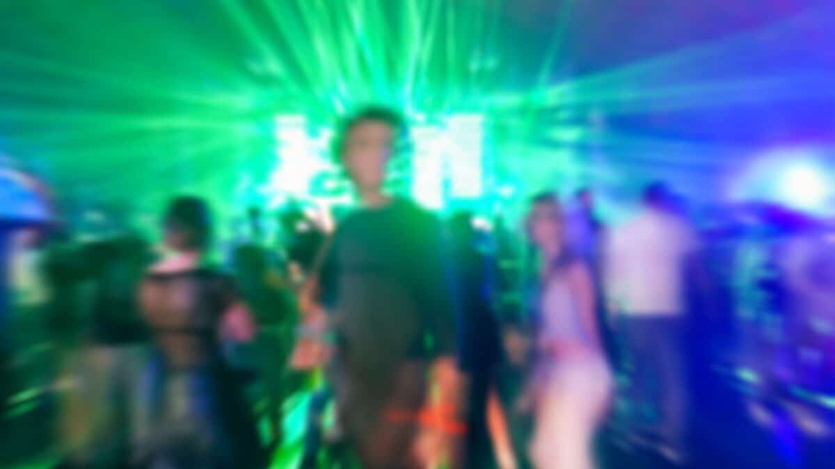 Blurred People dancing with original laser green lights in background - Defocused image of new generation disco club - Concept of nightlife with music - Blurry background